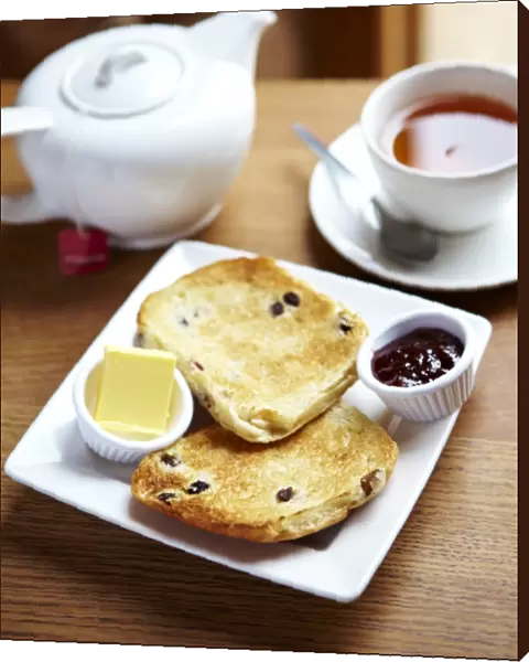 Teacake with butter and jam and a pot of tea N100359
