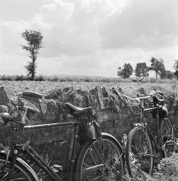 Bicycles AA082787. Two bicycles propped against a stone wall in Somerset