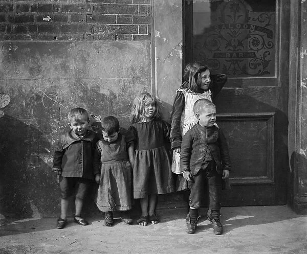 Children BB73_07074. A group of young children standing outside a public house, London