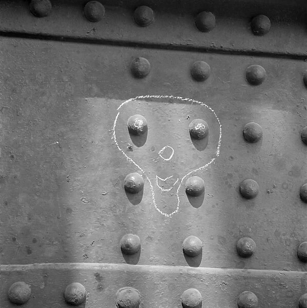 Face drawn in chalk around metal rivets, London Docks AA064944