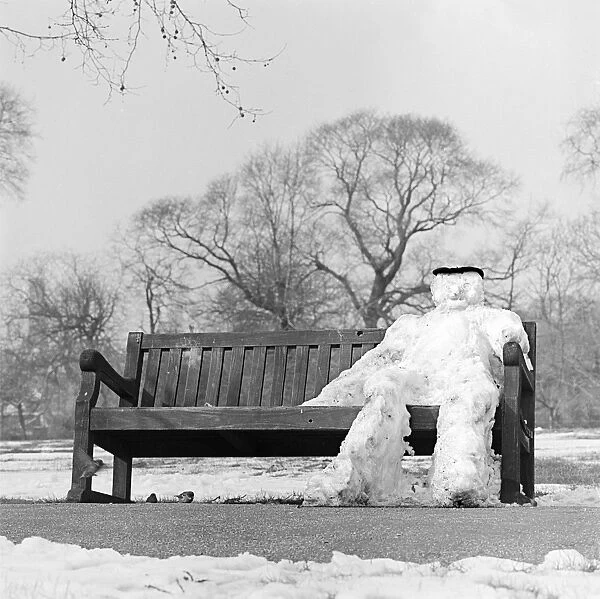 Snow man a073215. REGENTS PARK, London. A snowman sitting on a park bench